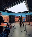 internal studio photo of a virtual production team in front of a large wall and under a bright light 