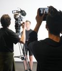 two men photographing and filming a stunt actor in a studio