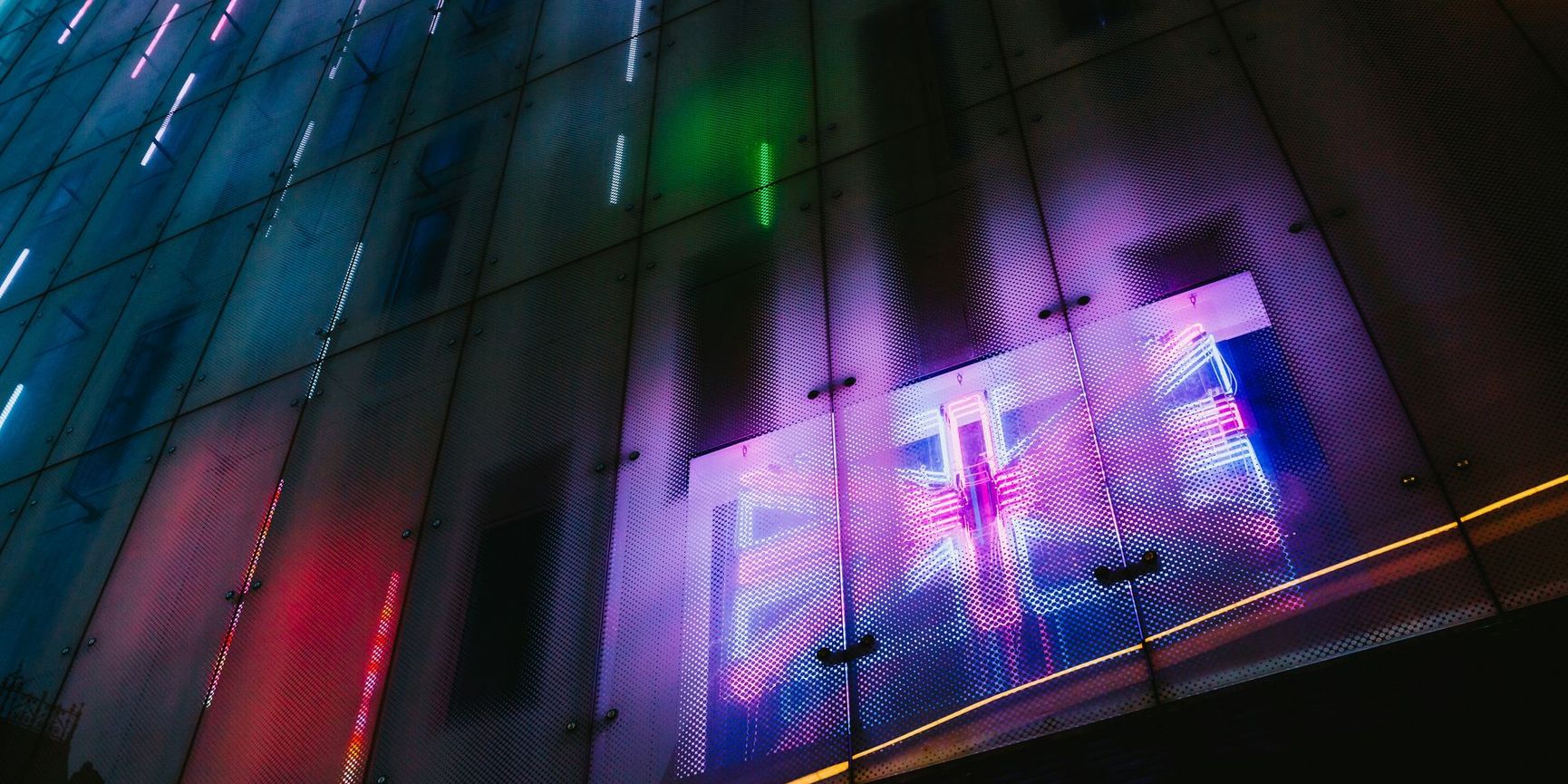 Glass building facade with led lights, and led UK flag visible behind it