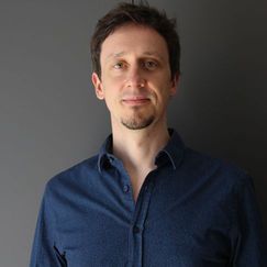 Headshot of dark-haired man dressed in a navy shirt.