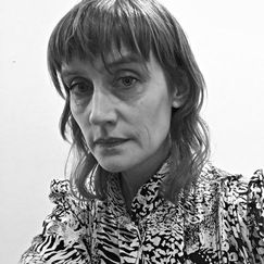 Black and white headshot of a woman in a patterned shirt.