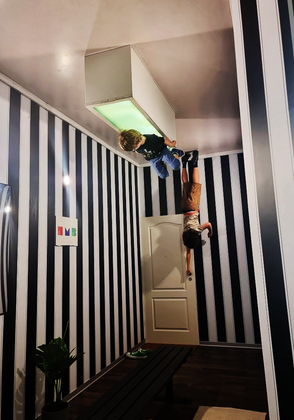 two children in a room that is upside down giving the illusion they are hanging from the ceiling