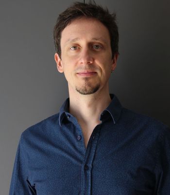 Headshot of dark-haired man dressed in a navy shirt.
