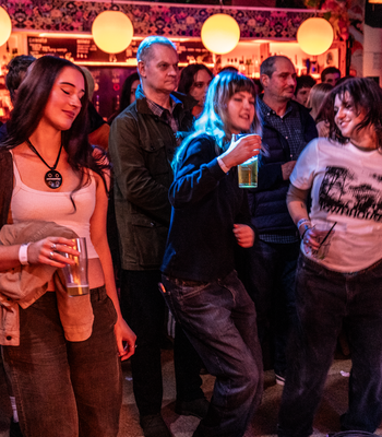 a group of women and men at a grass roots venue facing the stage and enyoying the music 
