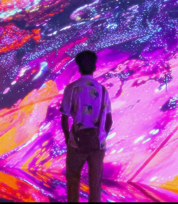 Man standing with back to view looking at large visual of pink swirling viscous pattern