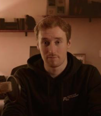 Rhys Murphy portrait - man with beard and hoodie sitting by microphone