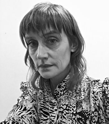 Black and white headshot of a woman in a patterned shirt.