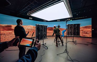 internal studio photo of a virtual production team in front of a large wall and under a bright light