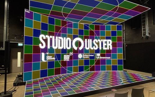The CoSTAR Screen Lab LED stage showing a colourful background of different coloured squares. There is a logo lock-up overlay including the logos of Studio Ulster and Ulster University.
