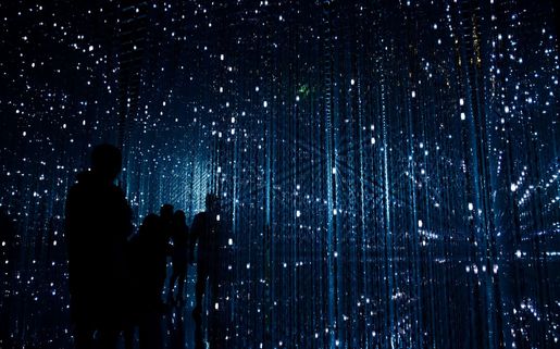  A person in a darkened space surrounded by large immersive digital projections, representing the kind of audience experiences being shaped by CoSTAR AI research