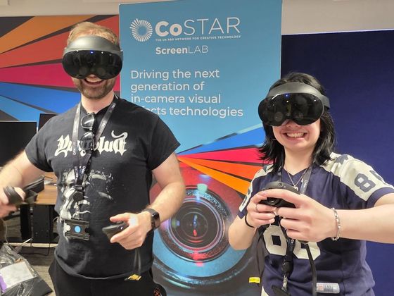 Two workshop participants wearing mixed reality headsets hold VR controllers while taking part in an interactive demonstration in front of CoSTAR Screen Lab branding.
