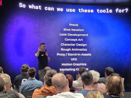 A speaker presents to a seated audience in front of a large presentation slide listing AI applications including previs, concept art, VFX and motion graphics at CoSTAR Screen Lab, Studio Ulster.