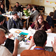 a group of about 20 diverse people in a room sat round tables taking part in a workshop with animated expressions