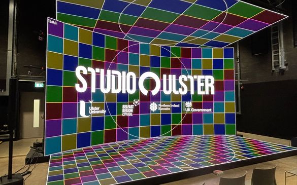 The CoSTAR Screen Lab LED stage showing a colourful background of different coloured squares. There is a logo lock-up overlay including the logos of Studio Ulster and Ulster University.