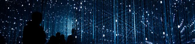  A person in a darkened space surrounded by large immersive digital projections, representing the kind of audience experiences being shaped by CoSTAR AI research