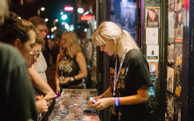 People around a merchandise desk at a grass roots gig