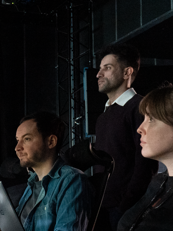 Diverse group of young People in a studio looking forward 2 women 3 men surrounded by laptops and wires